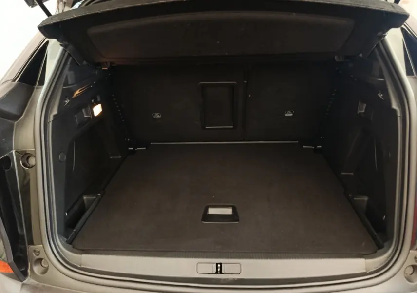 Coffre ouvert vu de l'arrière d'un Peugeot 3008 noir, espace de chargement propre et bien agencé.
