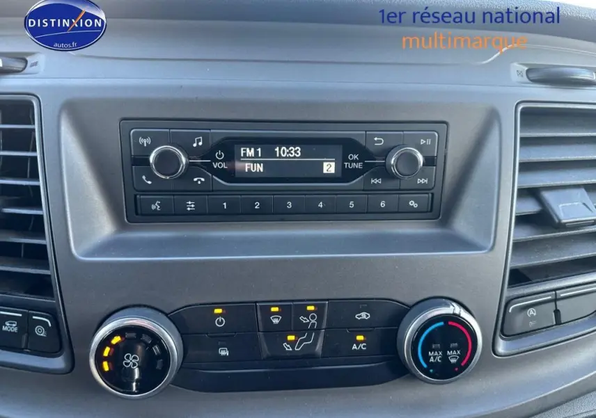 Tableau de bord du Ford Transit Custom blanc 2021, avec commandes climatisation et radio affichant FM1 à 10:33.
