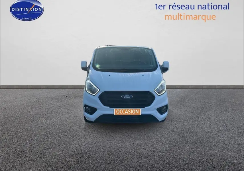Vue frontale d'un fourgon Ford Transit Custom blanc avec calandre noire et plaque "OCCASION" orange visible.