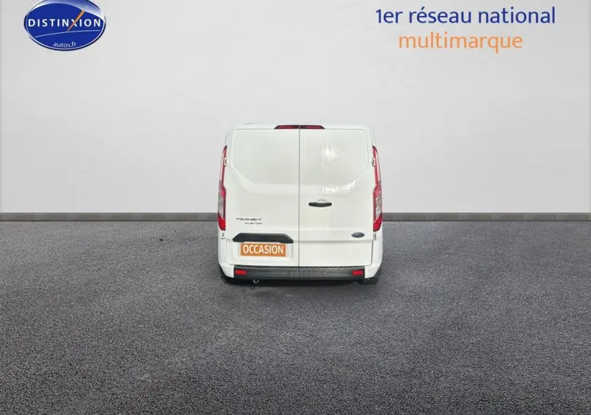 Vue arrière d'un fourgon Ford Transit Custom blanc avec portes battantes et plaque occasion visible.