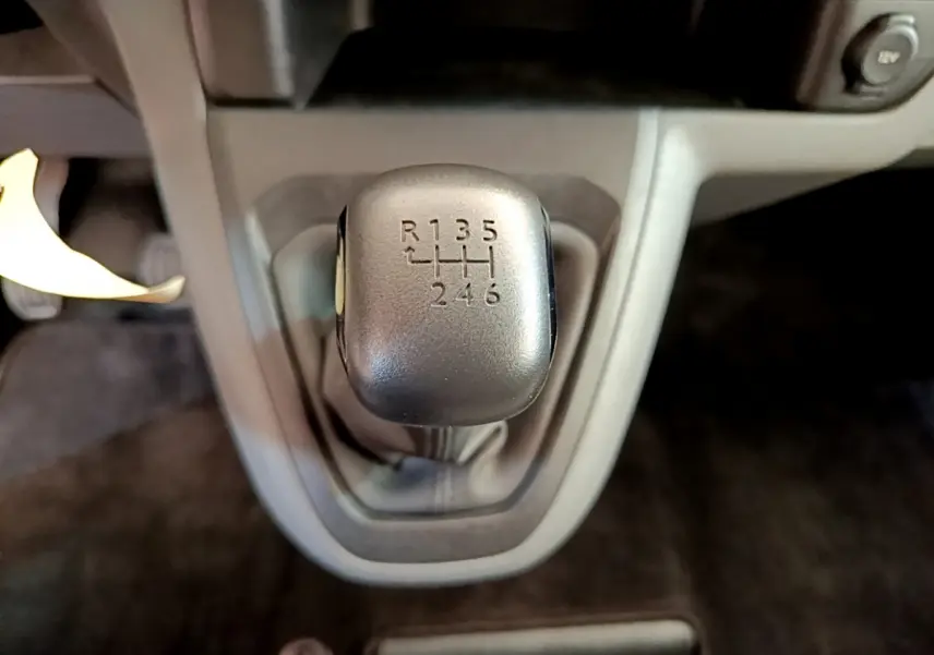 Gros plan sur le levier de vitesses manuel noir du Toyota Proace Verso gris clair, avec indication des 6 rapports et marche arrière.