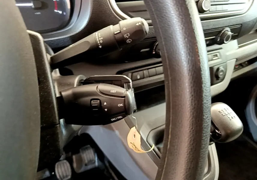 Vue rapprochée du volant et levier de vitesses manuel du Toyota Proace Verso gris clair, tableau de bord en arrière-plan.