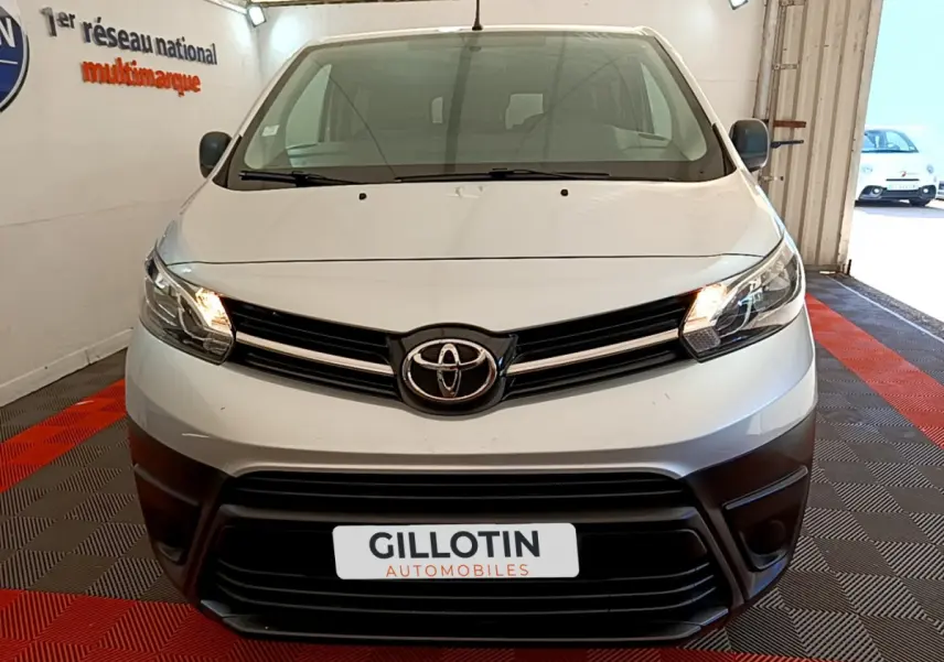 Vue frontale d'un Toyota Proace Verso gris clair avec phares allumés dans un showroom fermé