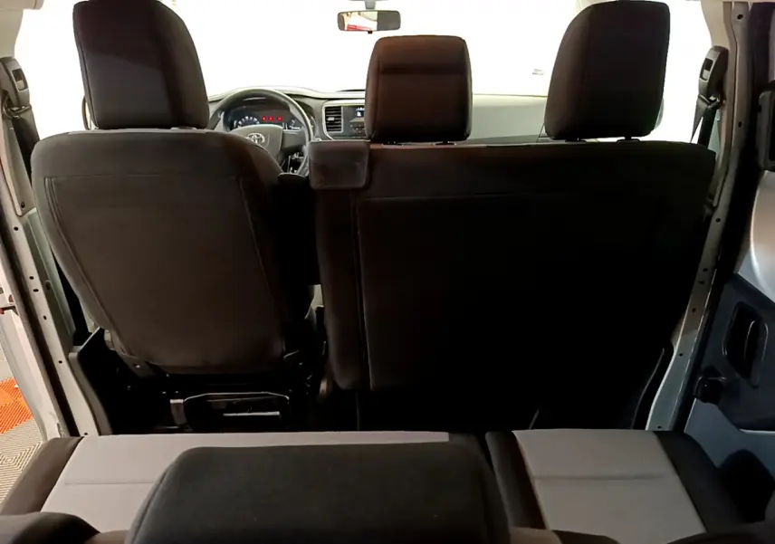 Vue arrière intérieure du Toyota Proace Verso 2019, sièges noirs et gris, tableau de bord et volant visibles au loin.