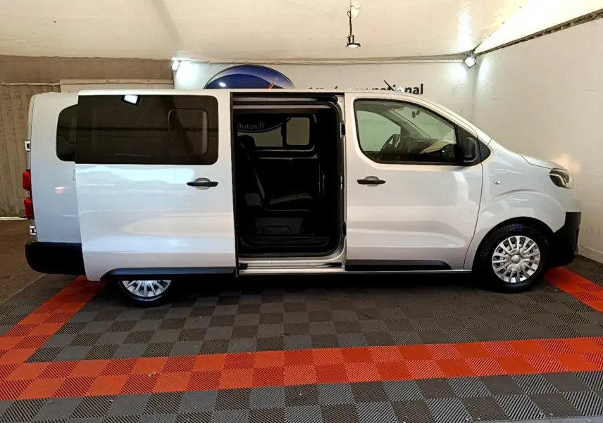 Vue latérale droite d'un Toyota Proace Verso gris clair avec porte coulissante ouverte montrant l'intérieur.