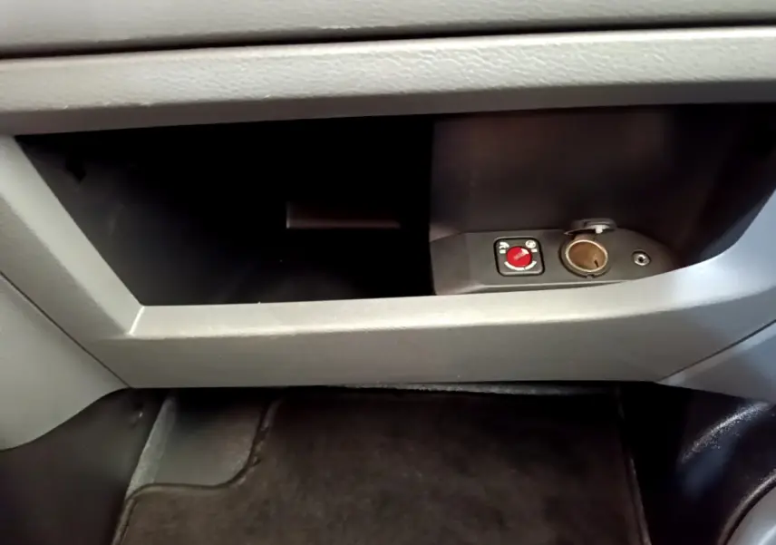 Gros plan sur la boîte à gants grise du Toyota Proace Verso 2019 avec prise 12V et commande rouge intégrée.