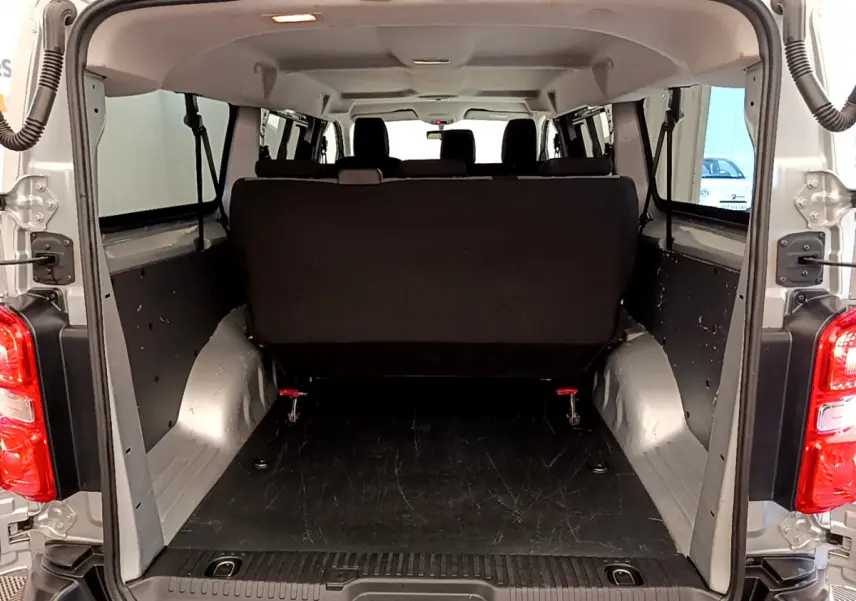 Vue arrière du coffre ouvert d'un Toyota Proace Verso gris clair, montrant l'espace de chargement et la banquette arrière noire.