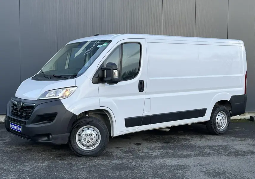Vue 3/4 avant droit d’un Opel Movano Fourgon blanc 2024 avec pare-chocs noirs et rétroviseurs électriques rabattables.