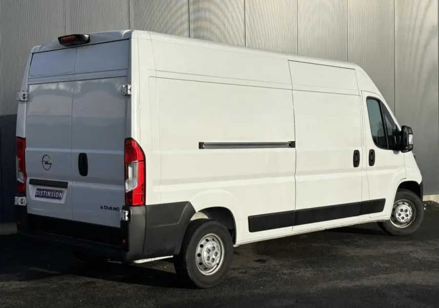 Vue 3/4 arrière droite d’un Opel Movano Fourgon blanc 2023 avec portes arrière battantes et protections noires.