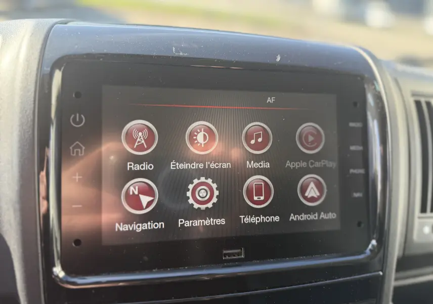 Vue 3/4 avant droit d’un Opel Movano Fourgon blanc 2023 avec calandre noire et phares LED, stationné devant un bâtiment industriel.