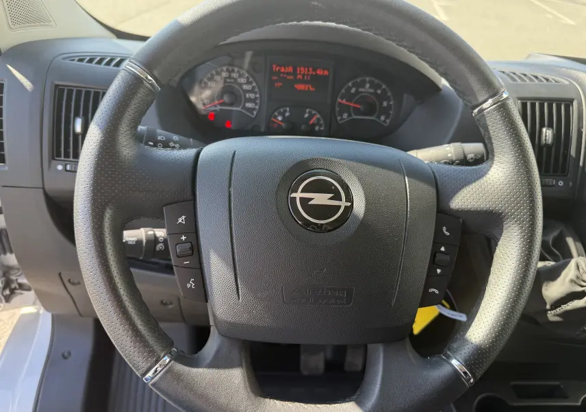 Vue de profil côté gauche d’un fourgon blanc Opel Movano 2023 avec porte latérale coulissante et protections noires.