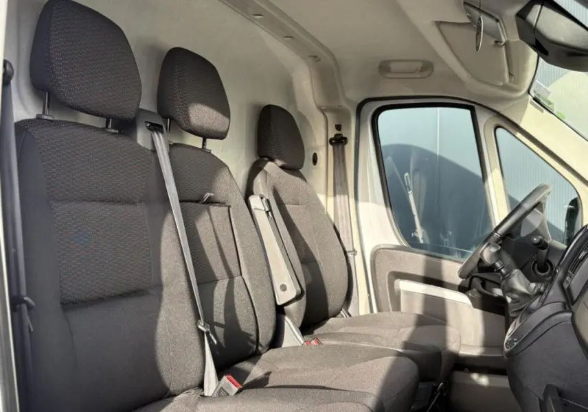 Vue intérieure côté droit montrant les trois sièges avant en tissu gris foncé du fourgon Opel Movano blanc.