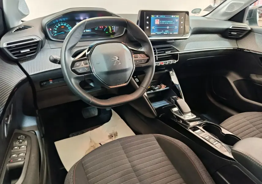 Vue intérieure côté conducteur du tableau de bord et volant cuir de la Peugeot 208 électrique Active Business R 2022.