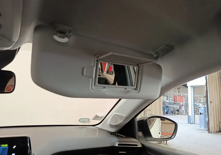 Intérieur du Peugeot 208 électrique blanc, vue sur pare-soleil avec miroir et rétroviseur côté droit.