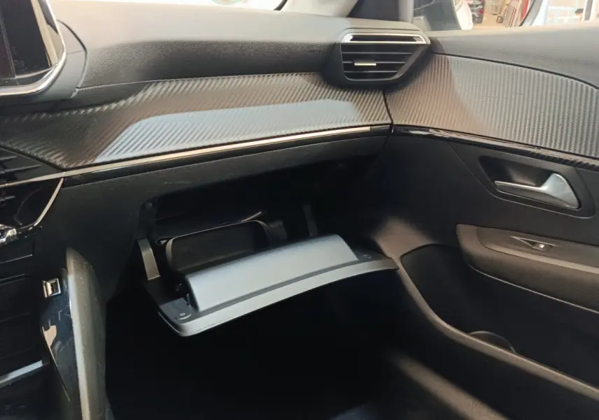 Intérieur côté passager de la Peugeot 208 électrique 2022, tableau de bord noir avec boîte à gants ouverte.