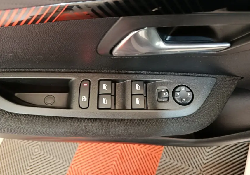 Commande des vitres électriques et réglage des rétroviseurs sur la porte côté conducteur d'une Peugeot 208 blanche électrique.