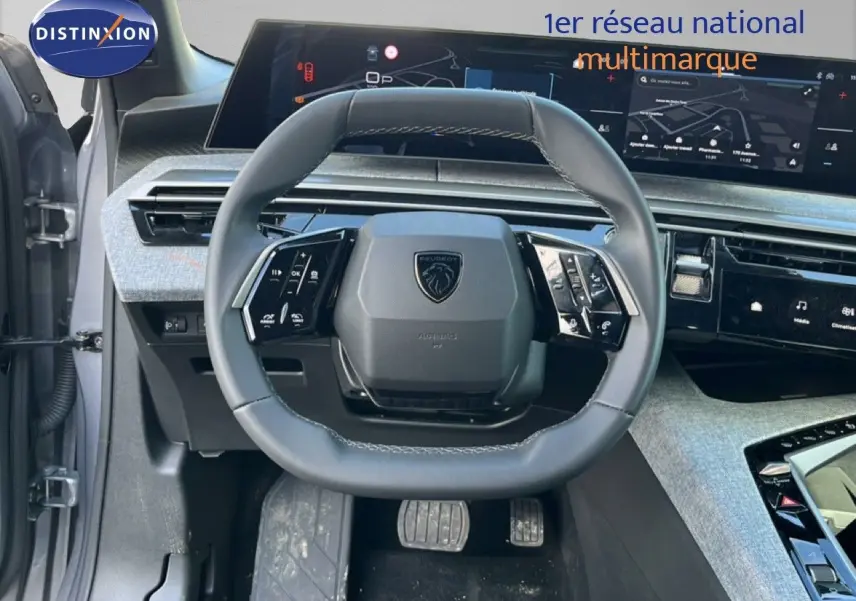 Vue centrée sur le volant cuir gris du Peugeot 5008 Hybrid 2025 avec tableau de bord numérique et écran tactile.