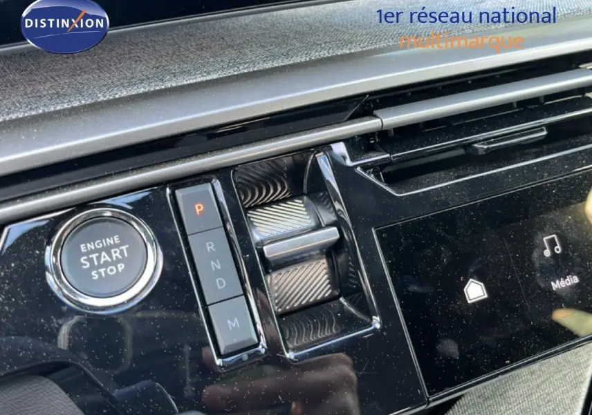 Gros plan sur la console centrale noire brillante du Peugeot 5008 gris, avec bouton start/stop et commandes de boîte automatique.