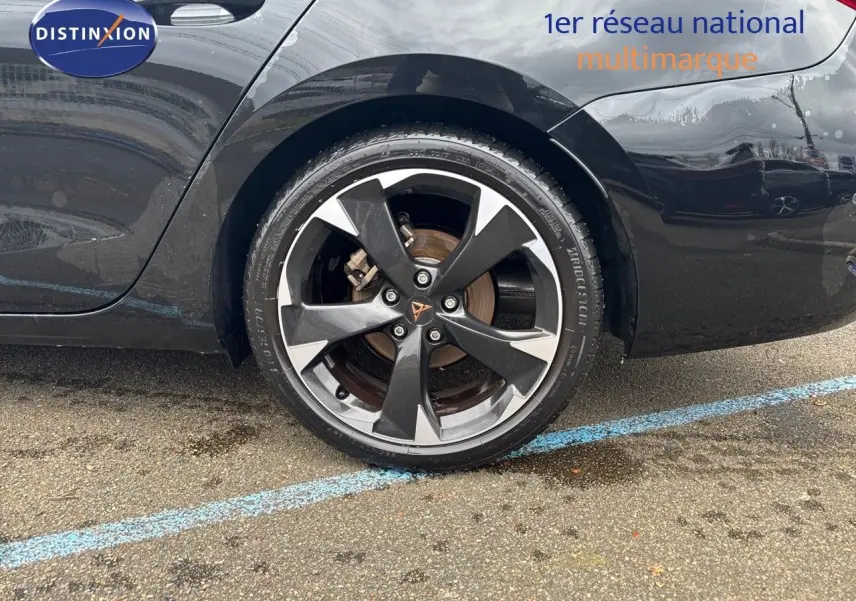 Gros plan sur la roue arrière droite d'une CUPRA LEON ST noire Midnight Metal avec jante bi-ton distinctive.