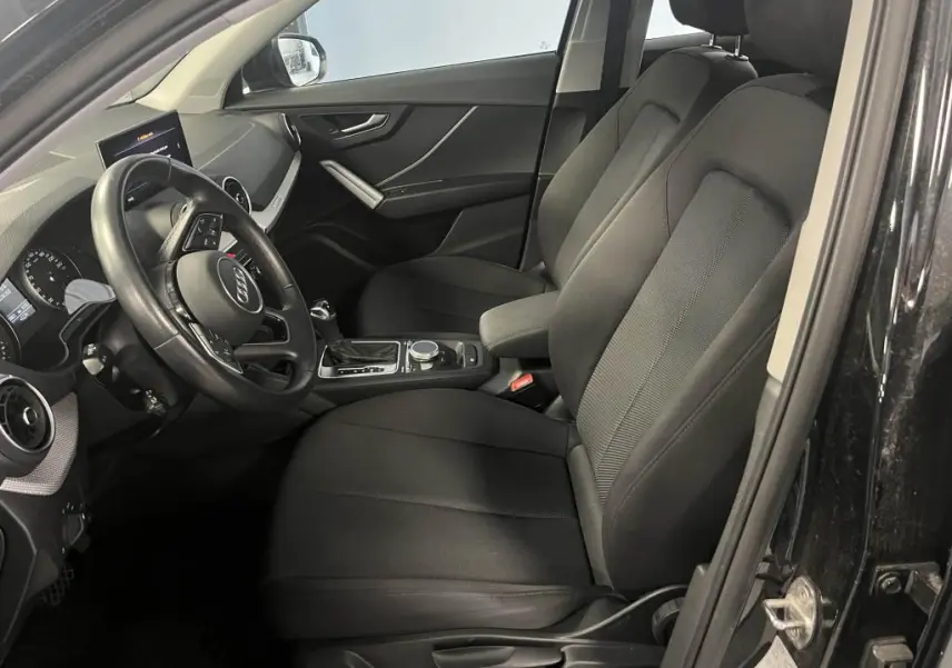 Intérieur noir de l'Audi Q2 2022 vu côté conducteur, avec volant cuir multifonction et console centrale moderne.