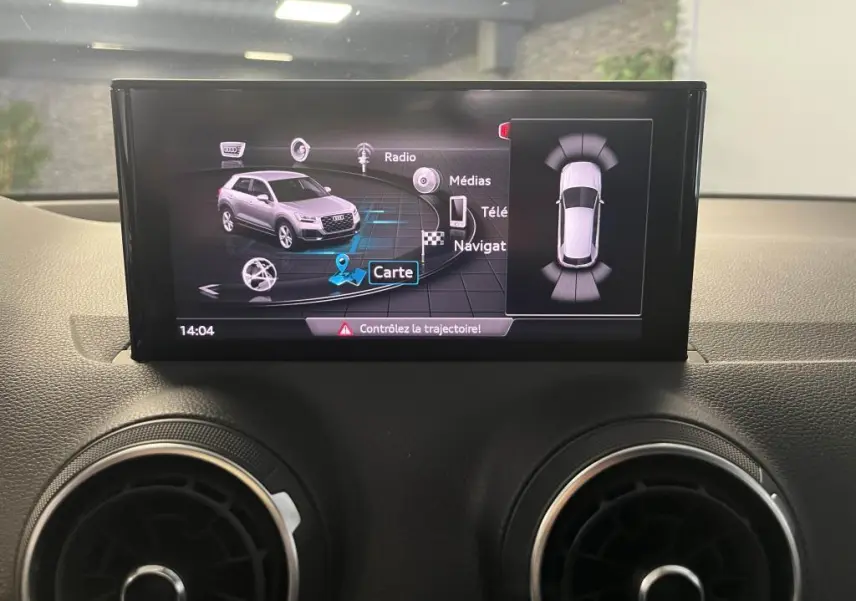 Écran central affichant la navigation et la vue 3D d'un Audi Q2 gris, avec alertes de trajectoire active.