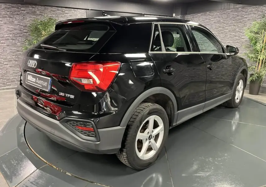 Audi Q2 noir brillant vue 3/4 arrière droit, avec jantes aluminium 5 branches et feux arrière LED rouges.