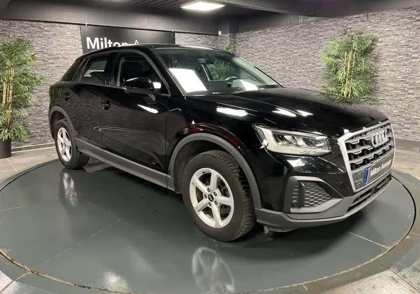 Audi Q2 noir brillant vue 3/4 avant droit, avec calandre chromée et jantes aluminium à 5 branches.