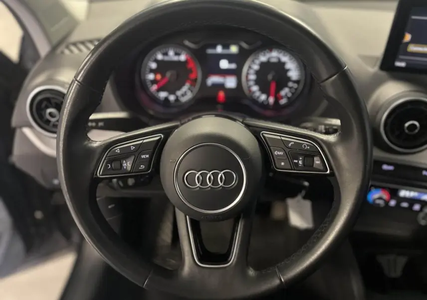 Volant en cuir noir multifonction d'Audi Q2 2022 avec tableau de bord et commandes visibles en arrière-plan.