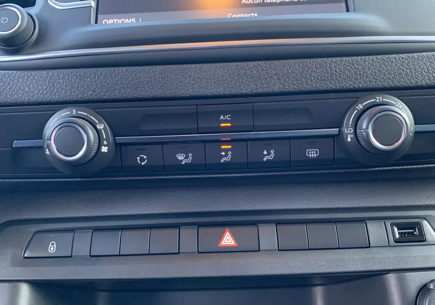 Vue rapprochée du tableau de bord noir du Fiat Scudo Combi électrique 2022, montrant les commandes de climatisation et les boutons de sécurité.