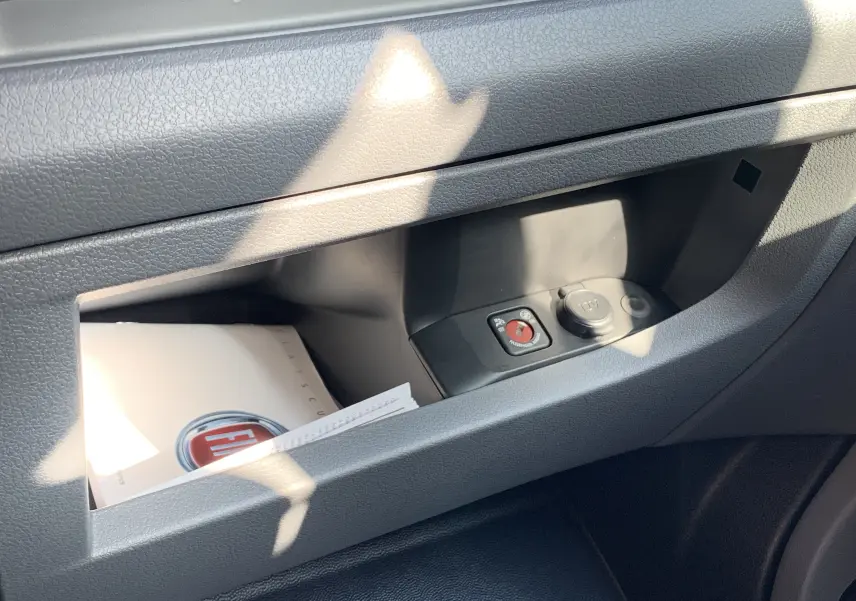 Rangement intérieur côté passager du Fiat Scudo Combi blanc, avec manuel et prise 12V visible.