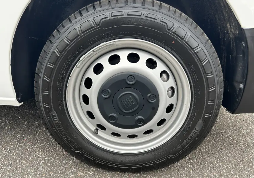 Gros plan sur la roue avant droite blanche d'un FIAT Scudo Combi électrique 2022 avec jante acier grise et logo FIAT central.