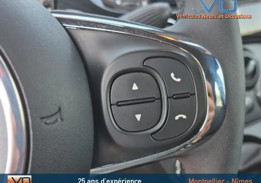 Gros plan sur les commandes de téléphonie au volant d'une FIAT 500C noire 2024 hybride essence.