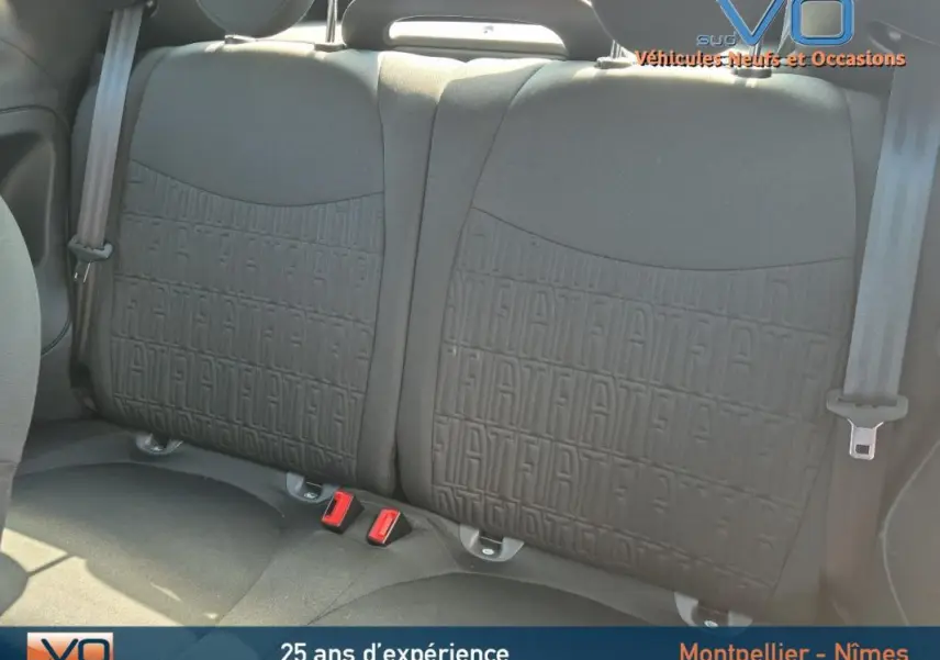 Gros plan sur les sièges arrière noirs de la Fiat 500C 2024, avec motif FIAT embossé et ceintures de sécurité visibles.