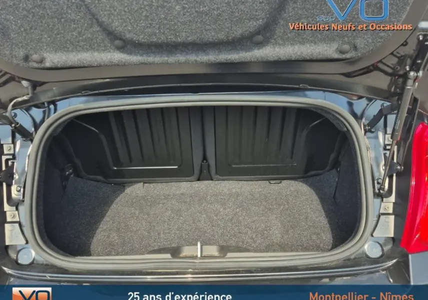 Coffre ouvert vu de dessus d'une FIAT 500C noire 2024 avec roue de secours visible sur le côté droit.