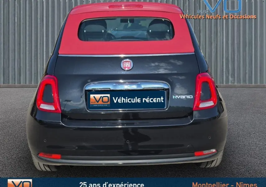 Vue arrière d'une FIAT 500C noire avec toit rouge, badge Hybrid et roue de secours visible sur le hayon.