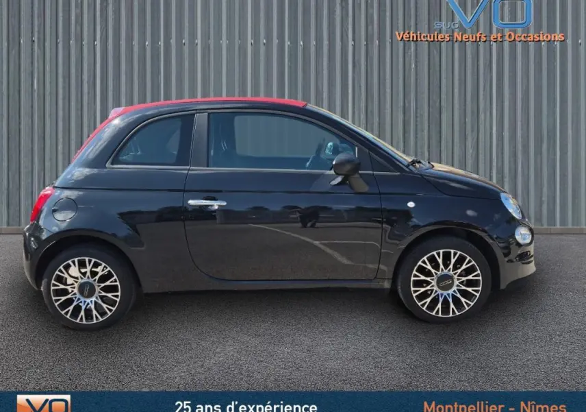 Profil côté gauche d'une FIAT 500C noire 2024 avec toit rouge et jantes alliage au design complexe, roue de secours visible.