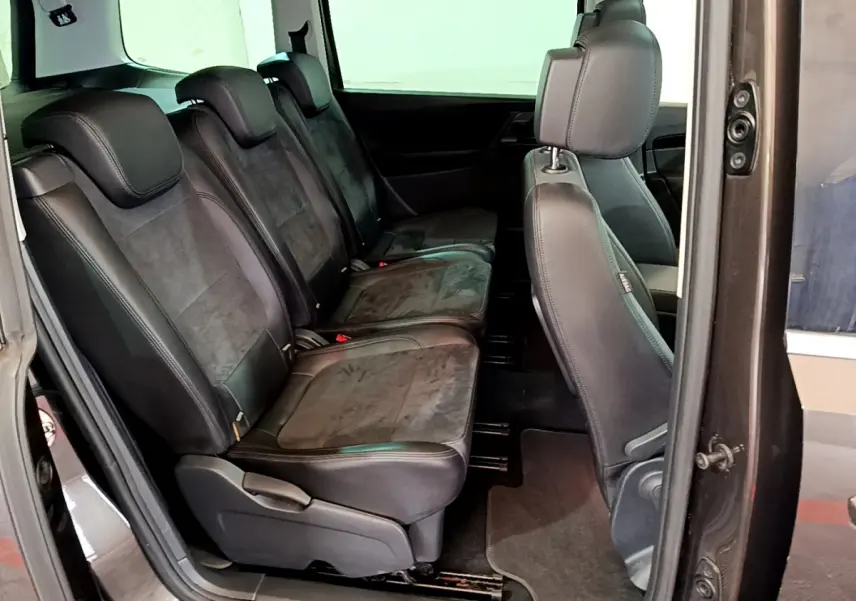 Vue latérale intérieure sur les sièges en cuir noir de la 2ème rangée du Volkswagen Sharan marron 2017.