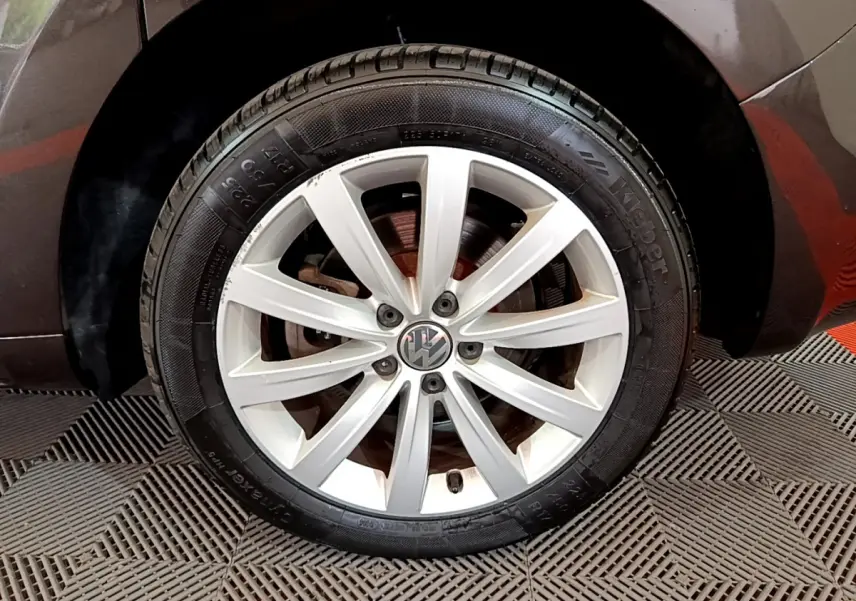 Gros plan sur la roue avant droite marron d'un Volkswagen Sharan 2017 avec jante alliage argentée à 10 branches.