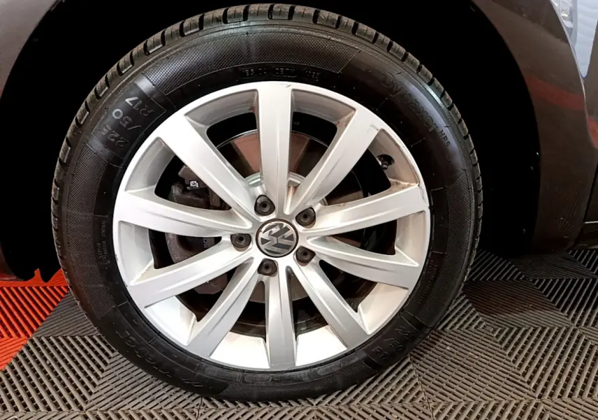 Gros plan sur la roue avant droite d’un Volkswagen Sharan marron, jante alliage argentée à 10 branches.