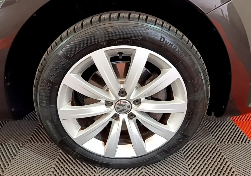 Gros plan sur la roue avant droite d'un Volkswagen Sharan marron, mettant en valeur la jante en alliage argentée.