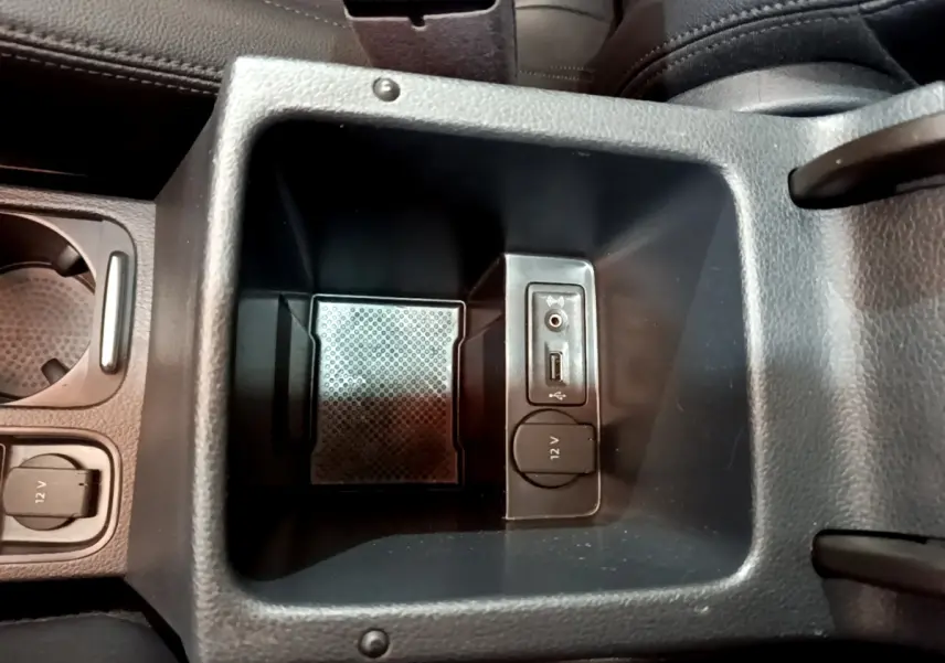 Vue rapprochée de la console centrale noire du Volkswagen Sharan 2017 avec prise 12V, USB et entrée audio auxiliaire.