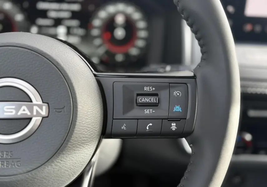 Gros plan sur le volant cuir noir du Nissan Qashqai 2025, avec commandes de régulateur et assistance à la conduite.