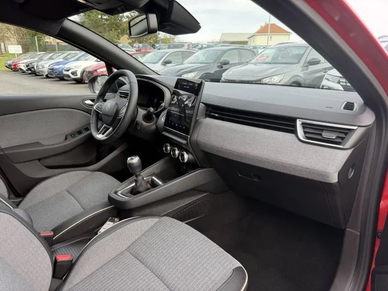 Vue intérieure côté conducteur de la Renault Clio 1.0 TCe 90ch Techno 2025 rouge Flamme avec tableau de bord moderne et boîte manuelle.