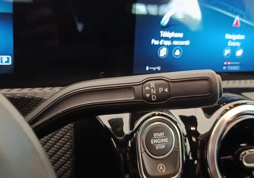 Gros plan intérieur sur la commande de boîte auto et bouton start/stop d’une Mercedes Classe A gris clair.