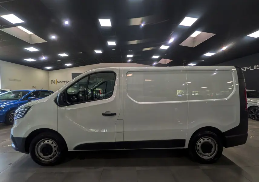 Vue latérale droite d’un Renault Trafic Fourgon blanc minéral 2024 en intérieur, avec jantes acier et carrosserie lisse.