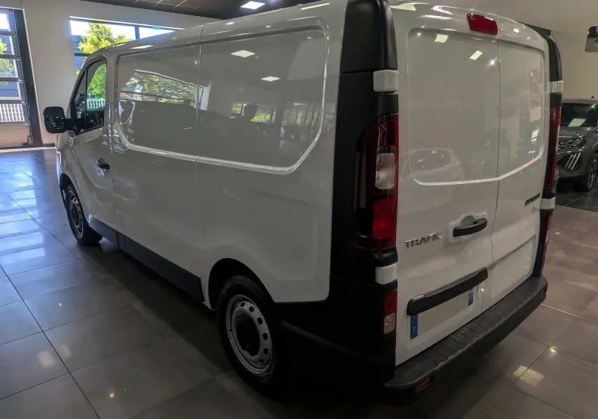 Vue 3/4 arrière droite du Renault Trafic Fourgon blanc minéral 2024, avec portes arrière battantes et feux verticaux.