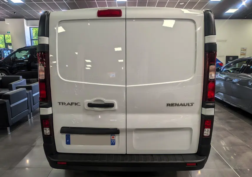Vue arrière d’un Renault Trafic Fourgon blanc minéral 2024 avec portes battantes et feux verticaux rouges.