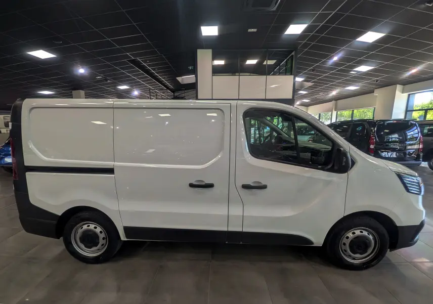 Vue de profil côté gauche du Renault Trafic Fourgon blanc minéral 2024, avec portes latérales coulissantes et jantes acier.