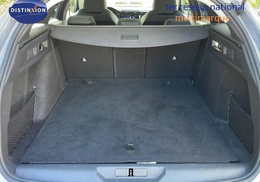 Vue du coffre spacieux et propre d'une Peugeot 308 SW Hybrid gris Artense métal, avec cache-bagages et sièges arrière visibles.