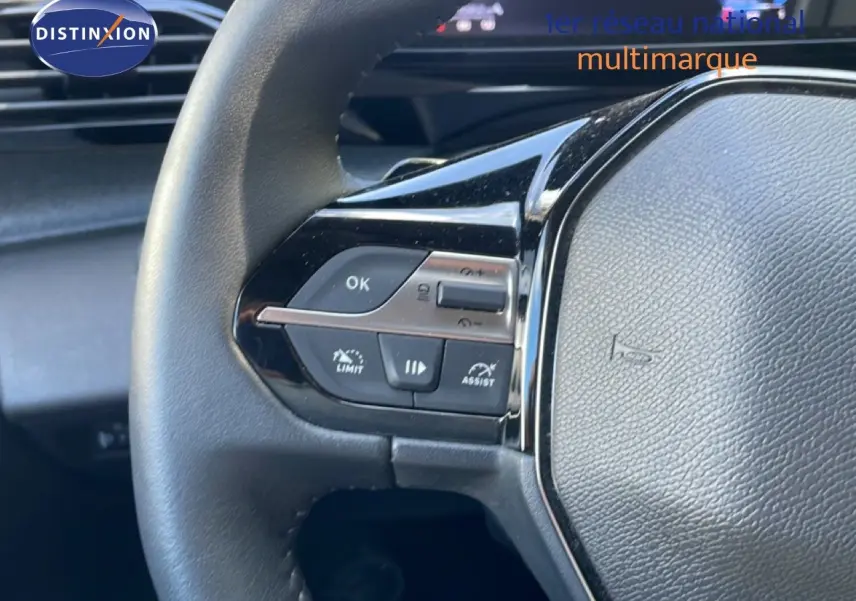 Gros plan sur le volant noir de la Peugeot 308 SW Hybrid 2025, montrant les commandes multifonctions côté gauche.